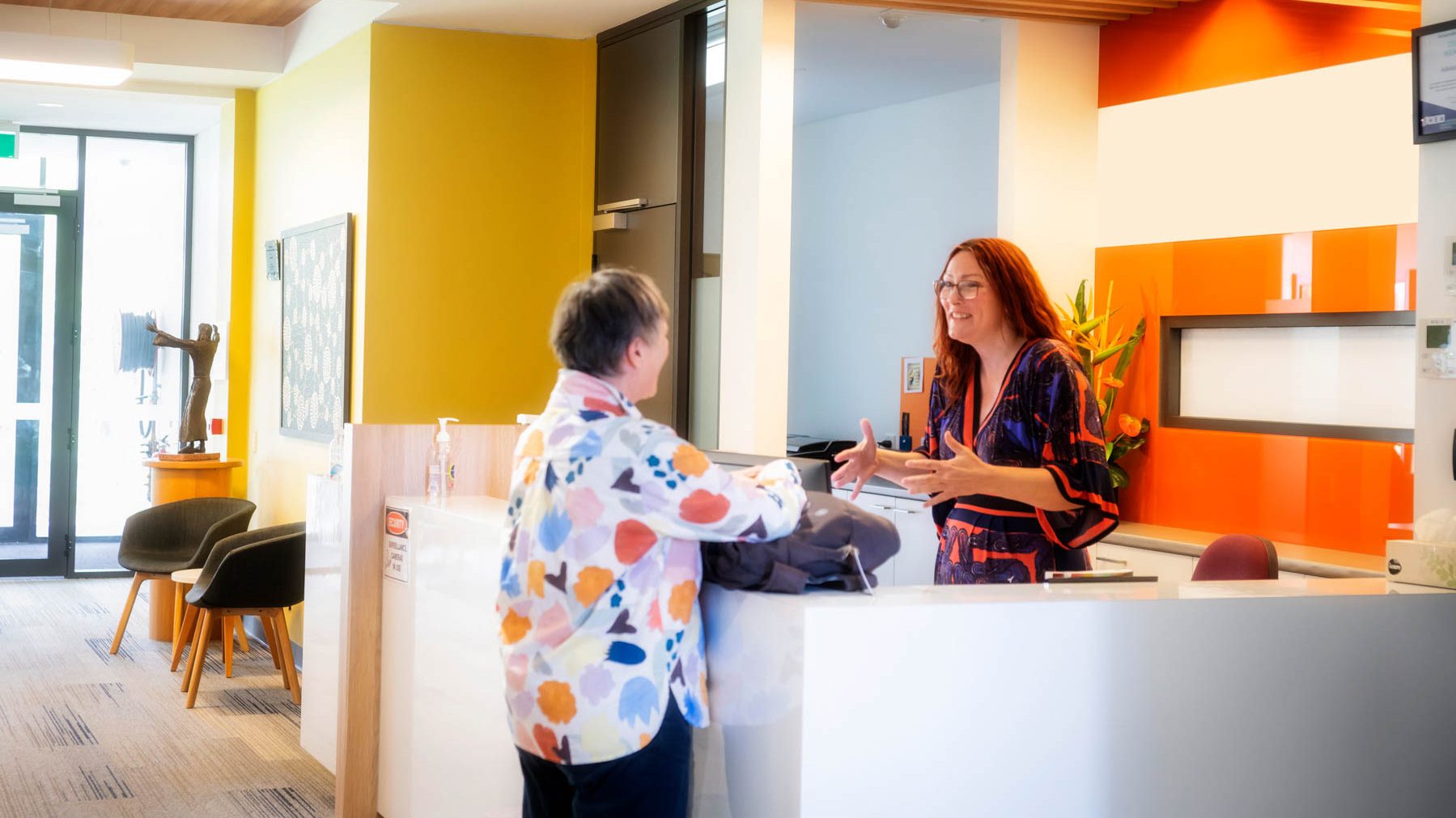 A student in a colourful shirt talks to a reception worker at Uniting College for Leadership and Theology