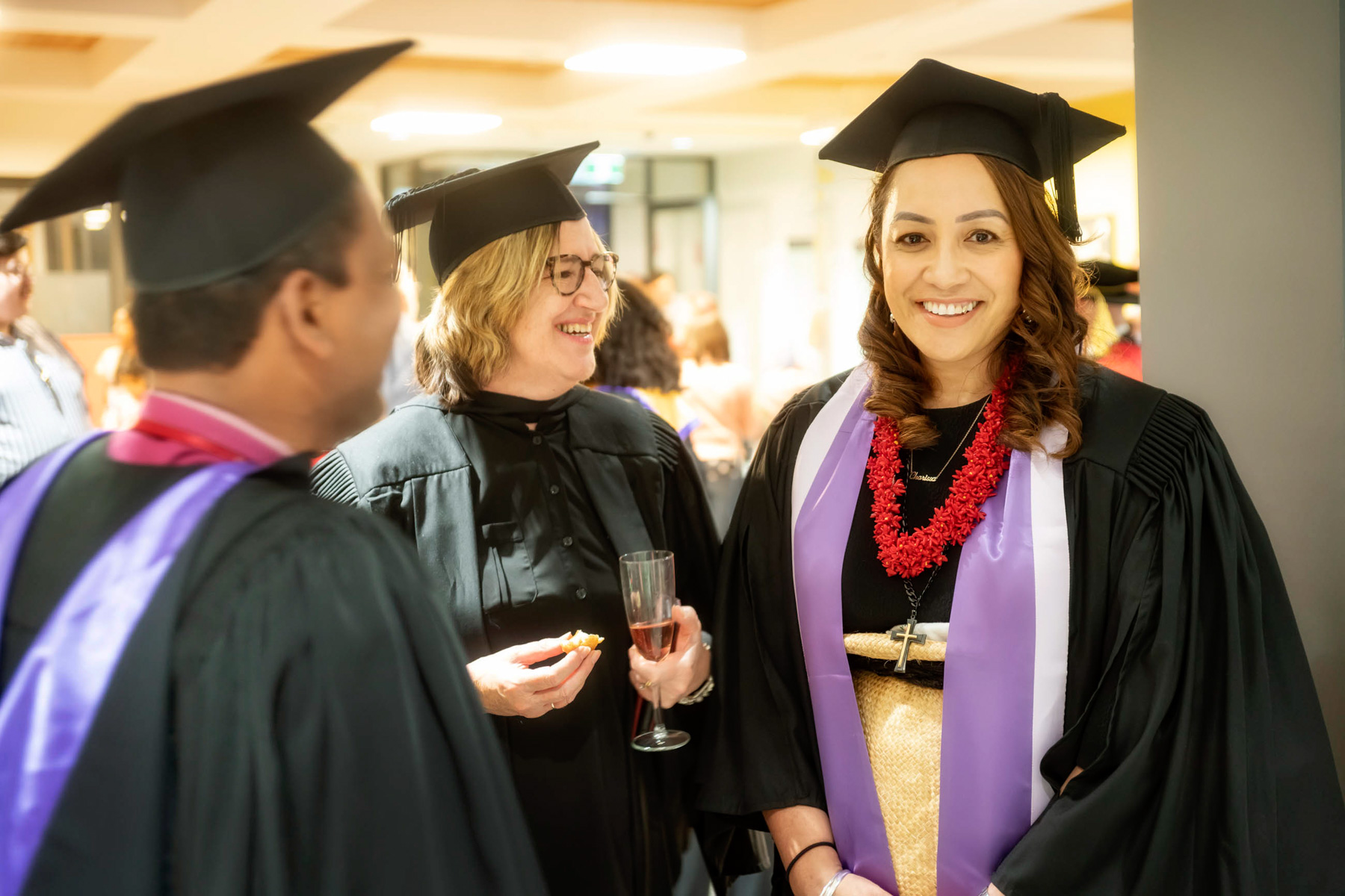 Three graduating students from Uniting College for Leadership and Theology smile and celebrate with food and drink