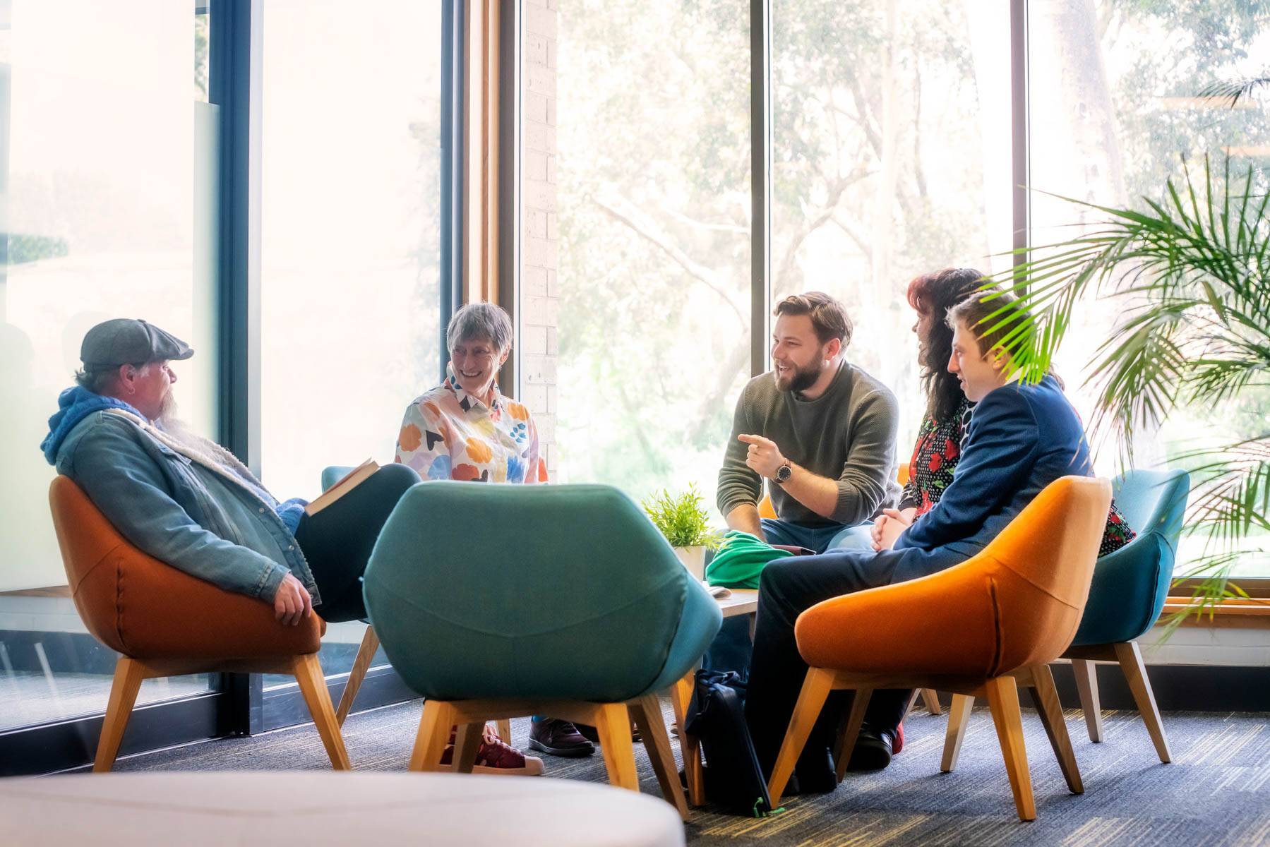 Several Uniting College for Leadership and Theology students sit around a table as one student points in agreement with another